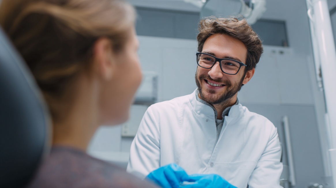 Tannlege snakker med pasient i behandlingsstol