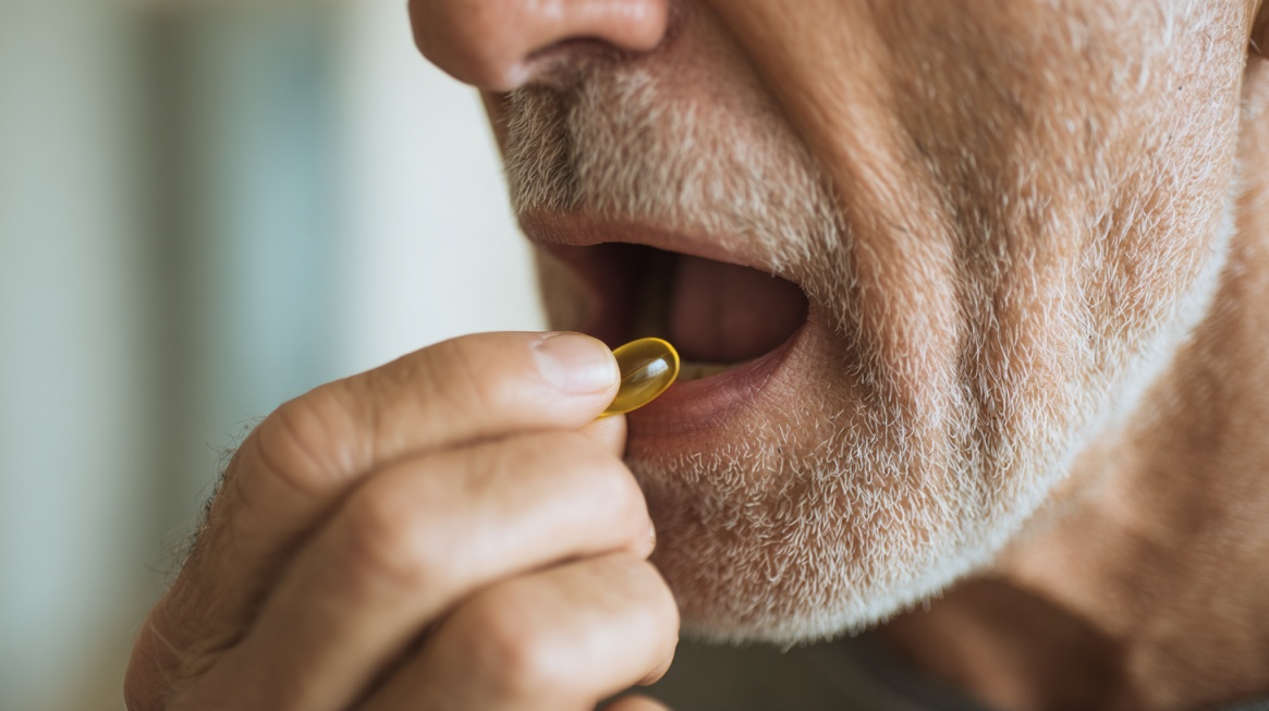 Eldre mann tar en kapsel med munnen åpen