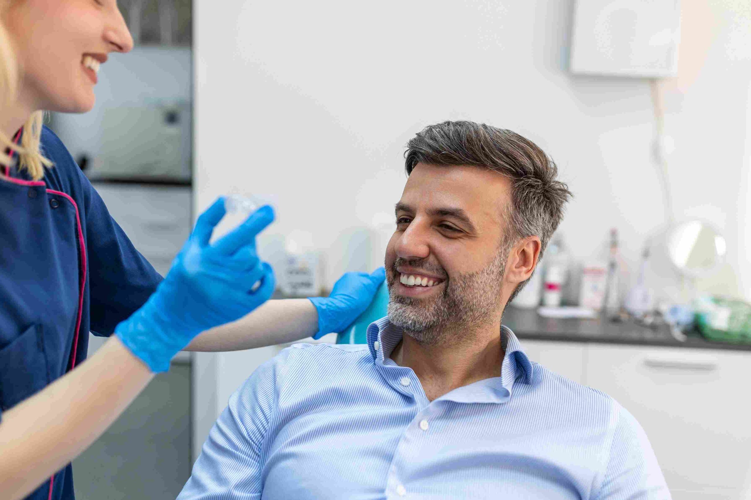 Pasient i tannlegestol snakker med behandler i klinikk